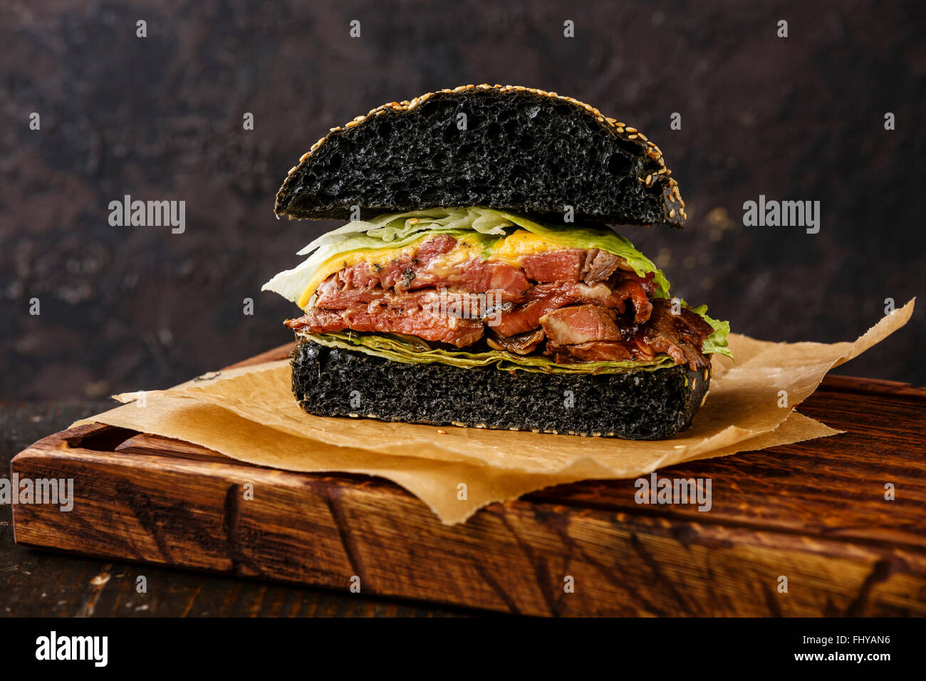 Rôti de bœuf coupé en deux avec des tranches de Pastrami Burger sur fond sombre Banque D'Images