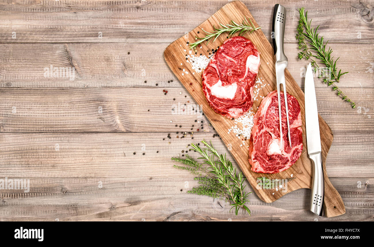 La viande crue. Ribeye Steak avec des herbes et épices sur cuisine en bois 24. Arrière-plan de l'alimentation Banque D'Images