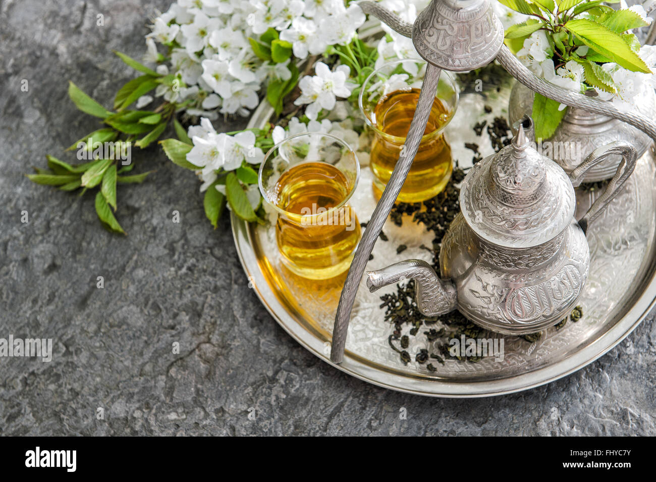 Verres à thé et pot, sucreries traditionnelles. Le tableau avec les fleurs du printemps Banque D'Images