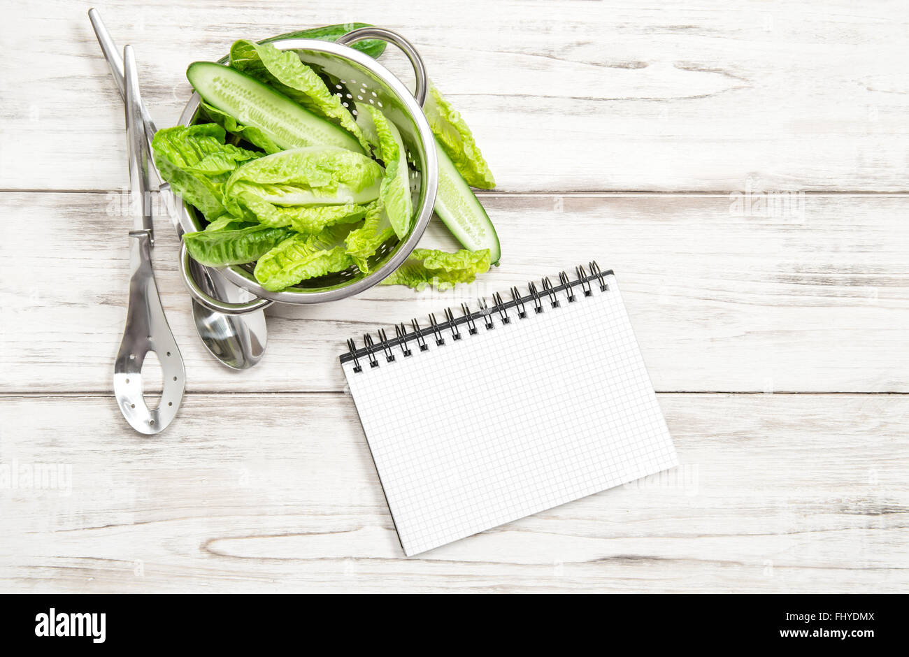Feuilles de salade verte et livre blanc sur la table de cuisine en bois. Concept d'aliments sains Banque D'Images