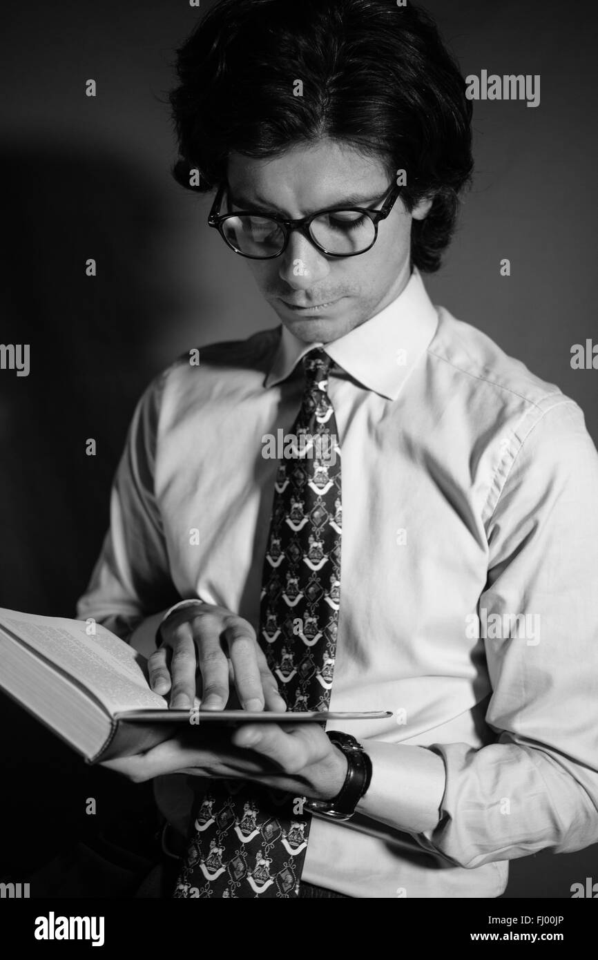 Jeune homme lisant un livre avec des lunettes. Banque D'Images