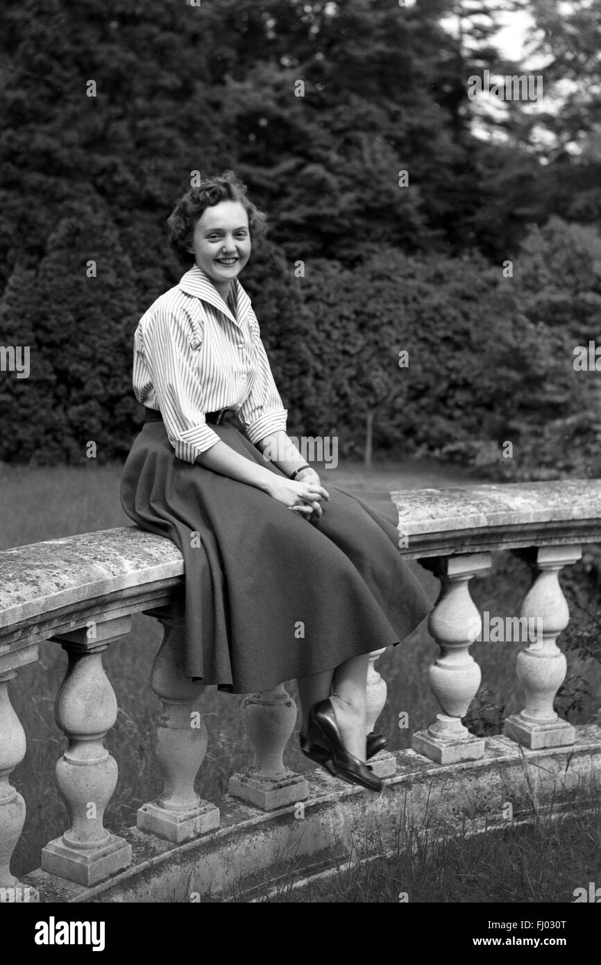 Young female student sitting on wall robuste Banque D'Images