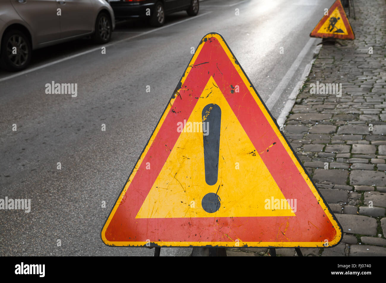 Triangle rouge et jaune lumineux de signalisation d'avertissement avec point d'exclamation sur le bord de la route Banque D'Images