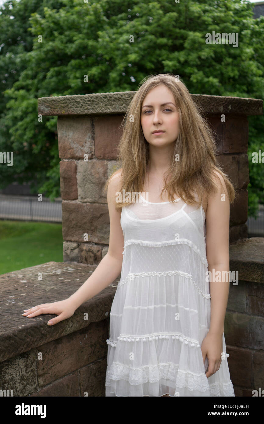Femme sérieuse dans vintage robe blanche standing outdoors Banque D'Images