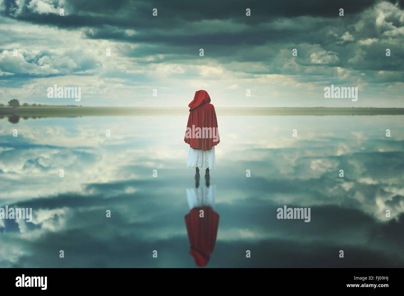 Femme à capuche rouge dans un étrange paysage avec des nuages. Fantasy et surréaliste Banque D'Images