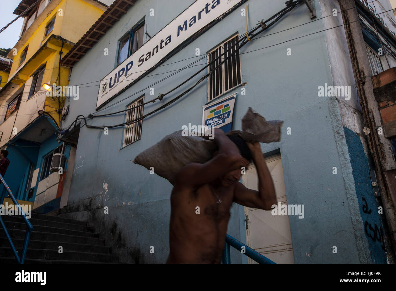 L'homme passe devant l'UPP de Favela Santa Marta à Rio de Janeiro, Brésil. Depuis 2008 Santa Marta a une unité de police de pacification ( Unidade de Polícia Pacificadora, aussi traduit par unité de police pacificatrice ), en abrégé l'UPP, l'application de la loi et un programme de services sociaux qui vise à reconquérir les territoires, plus communément favelas, contrôlé par des gangs de trafiquants de drogue. Banque D'Images