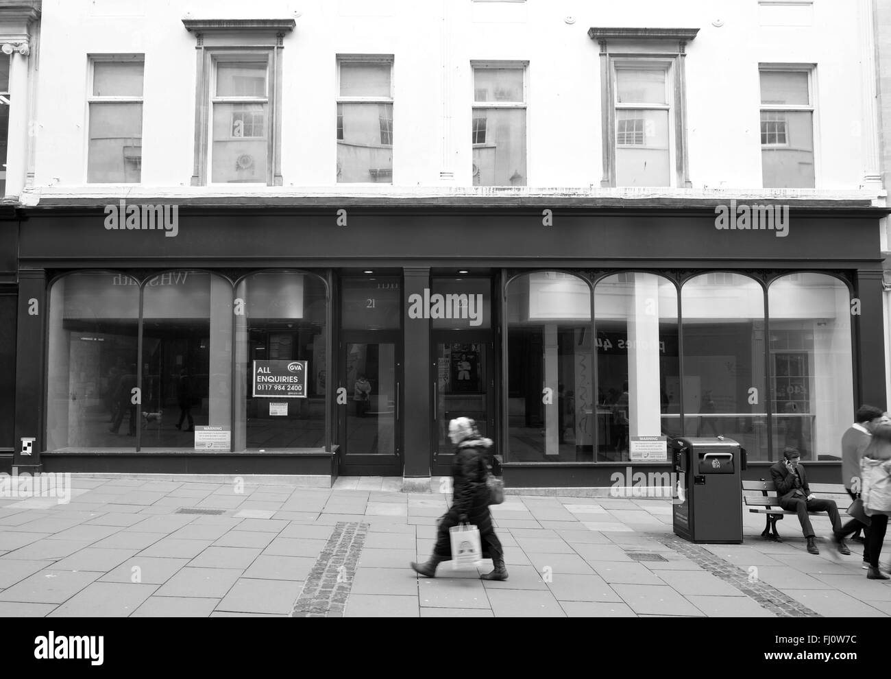 Femme seule marchant devant un grand magasin vide dans le centre de Bath. Février 2016 Banque D'Images