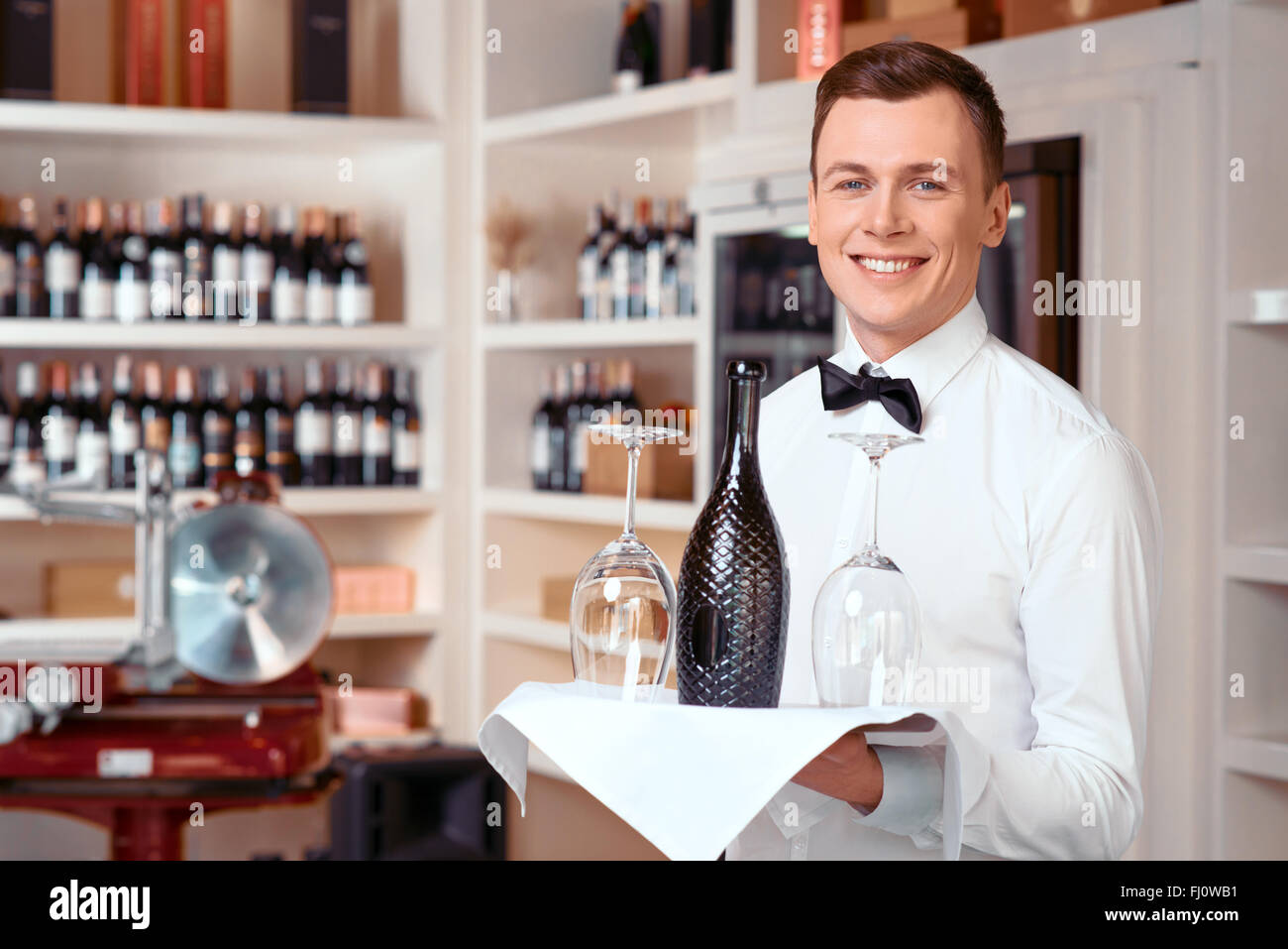 Sommelier agréable holding tray with wine bottle Banque D'Images