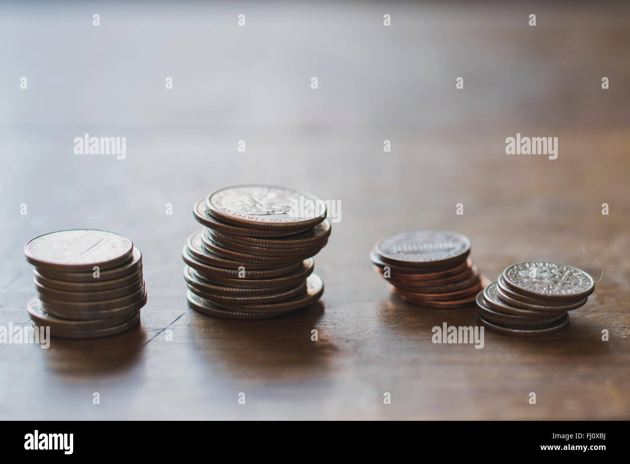 Piles inégales d'entre nous de pièces sur une table en bois Banque D'Images