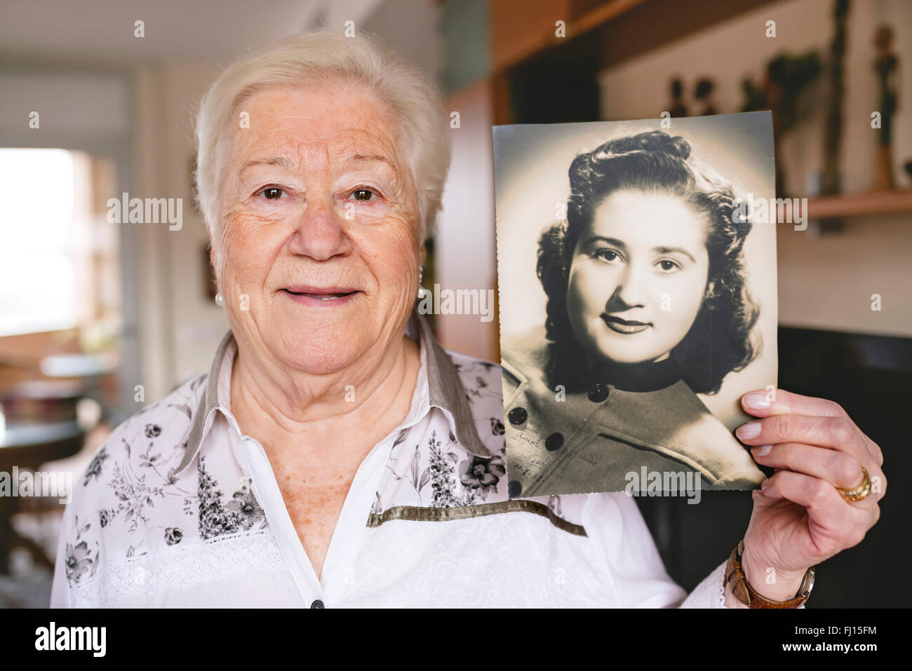Portrait of senior woman montrant une vieille photo d'elle-même Banque D'Images