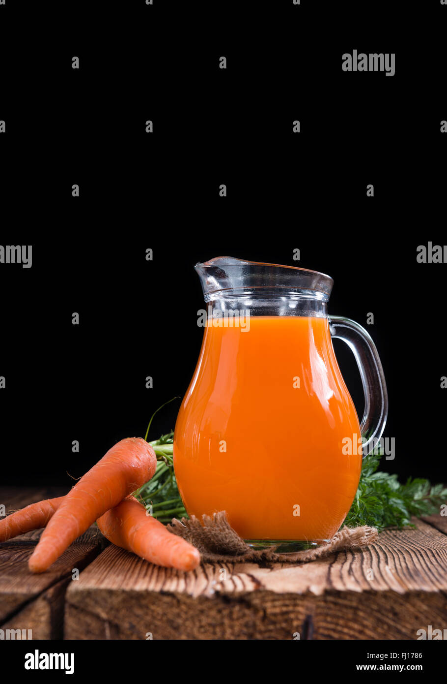 Partie de jus de carotte sur une vieille table en bois (selective focus) Banque D'Images