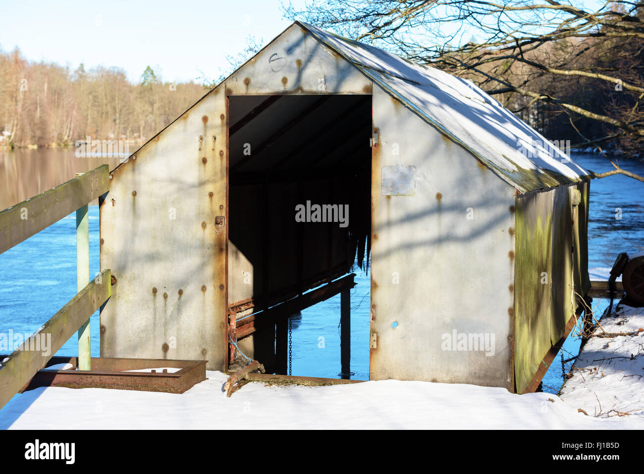 Un petit hangar à bateaux de fortune abandonnées sur la rivière. La neige au sol. Banque D'Images