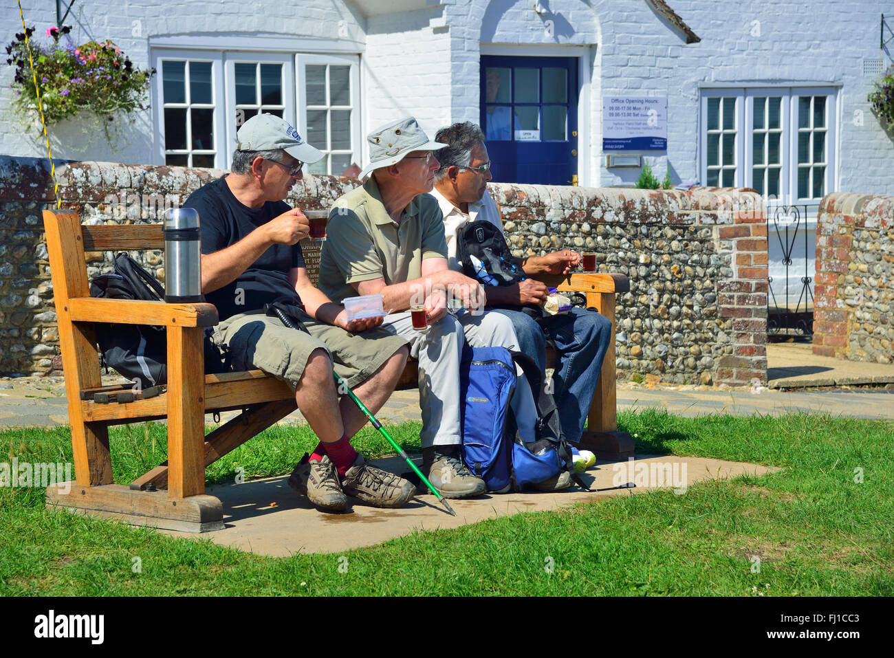 Trois marcheurs sont assis sur un siège pour une tasse de thé dans le village d'Itchenor, Chichester Harbour, West Sussex, Angleterre, Royaume-Uni Banque D'Images