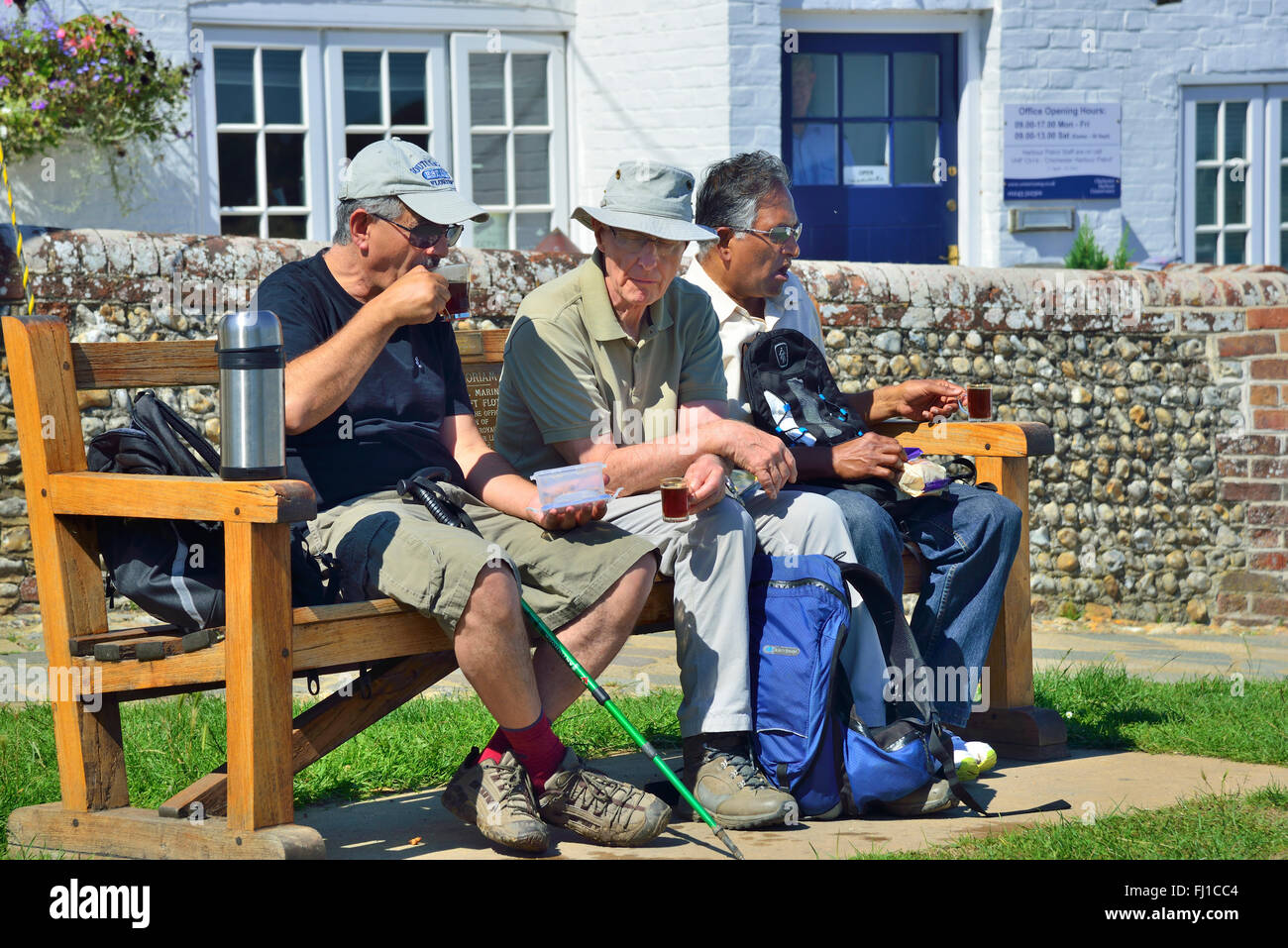 Trois marcheurs sont assis sur un siège pour une tasse de thé dans le village d'Itchenor, Chichester Harbour, West Sussex, Angleterre, Royaume-Uni Banque D'Images