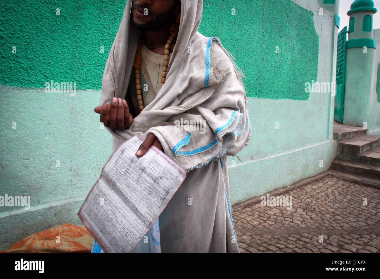 Un mendiant montre un livre avec écritures arabes à l'intérieur en face de la vieille mosquée de coity de Harar, en Ethiopie Banque D'Images