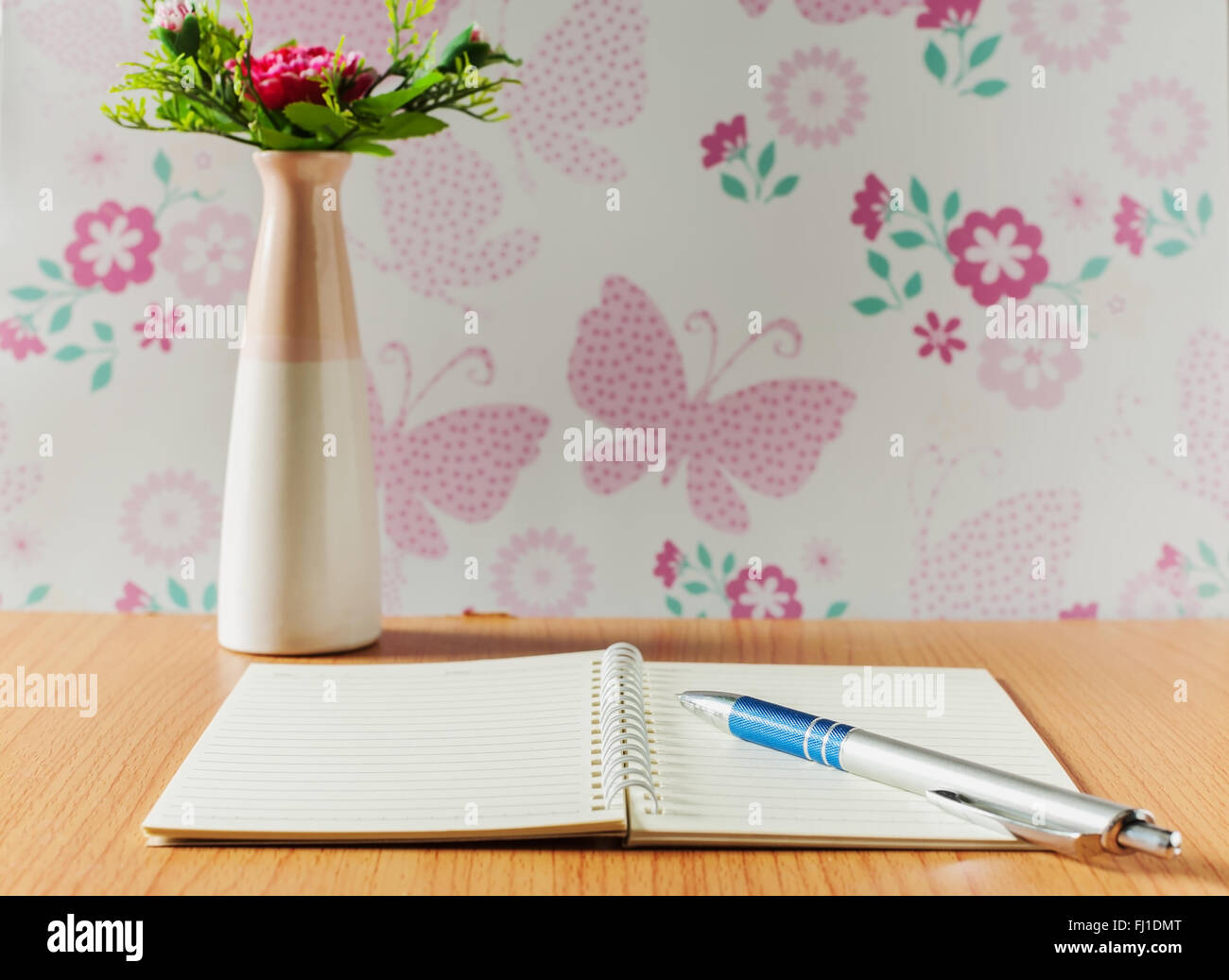 Bloc-notes avec un stylo et un vase sur la table de bureau Banque D'Images