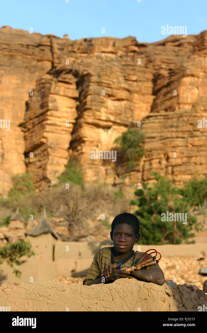Un garçon pose en haut de maison traditionnelle en pays Dogon, au Mali Banque D'Images
