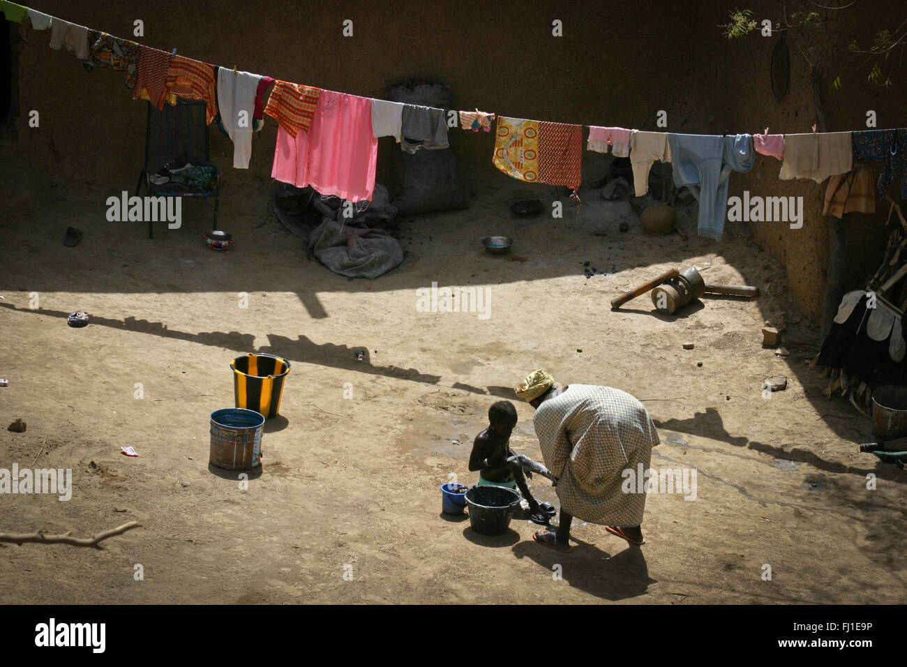 Une mère, c'est laver sa fille dans la cour d'une maison en banco de boue traditionnelles Djenné, Mali, Afrique du Sud Banque D'Images