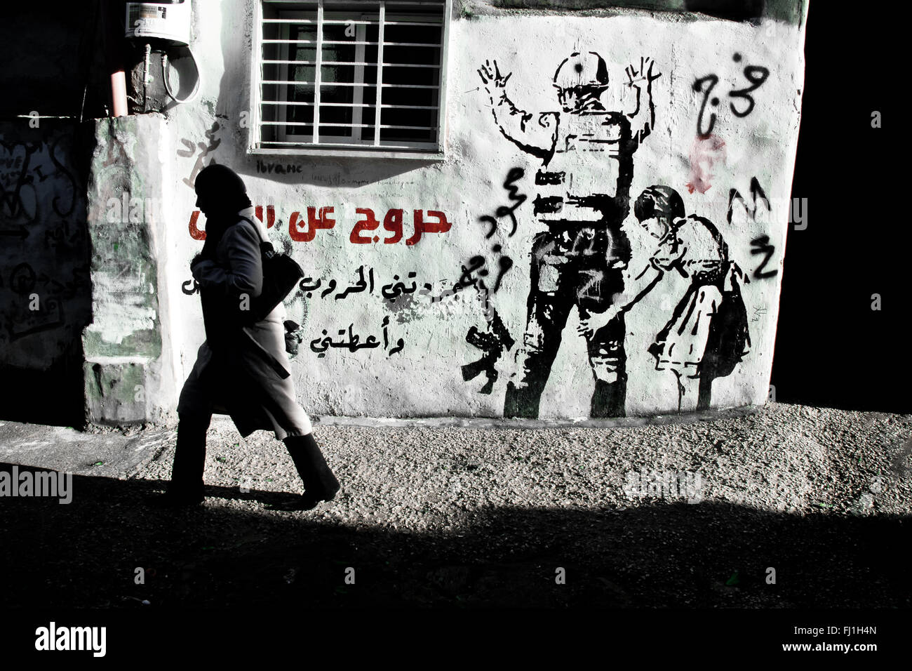 Banksy peinture , femme marche dans le camp de réfugiés de Dheisheh - Bethléem - Palestine Banque D'Images