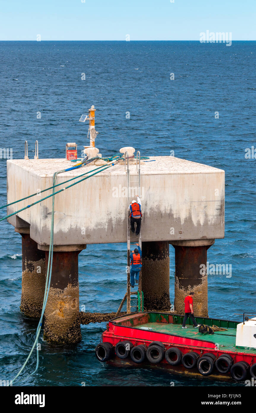 Dockers grimper sur la plate-forme d'amarrage à larguer les amarres dans le port de Puerto Madryn Banque D'Images