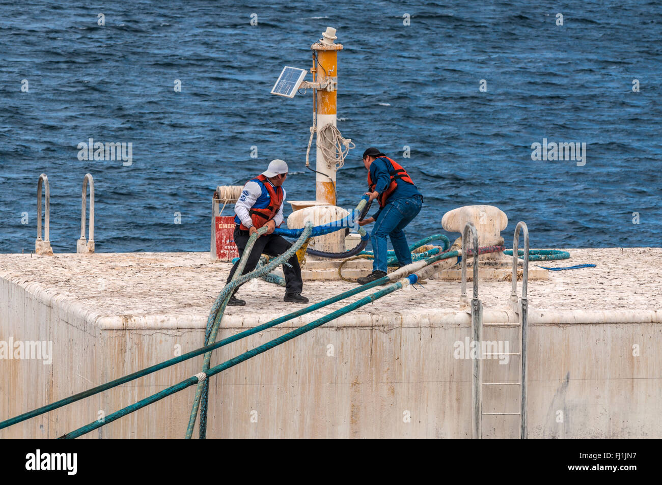 Sur la plate-forme d'un jette son travailleurs l'amarrage d'un navire en câble Harbour Banque D'Images