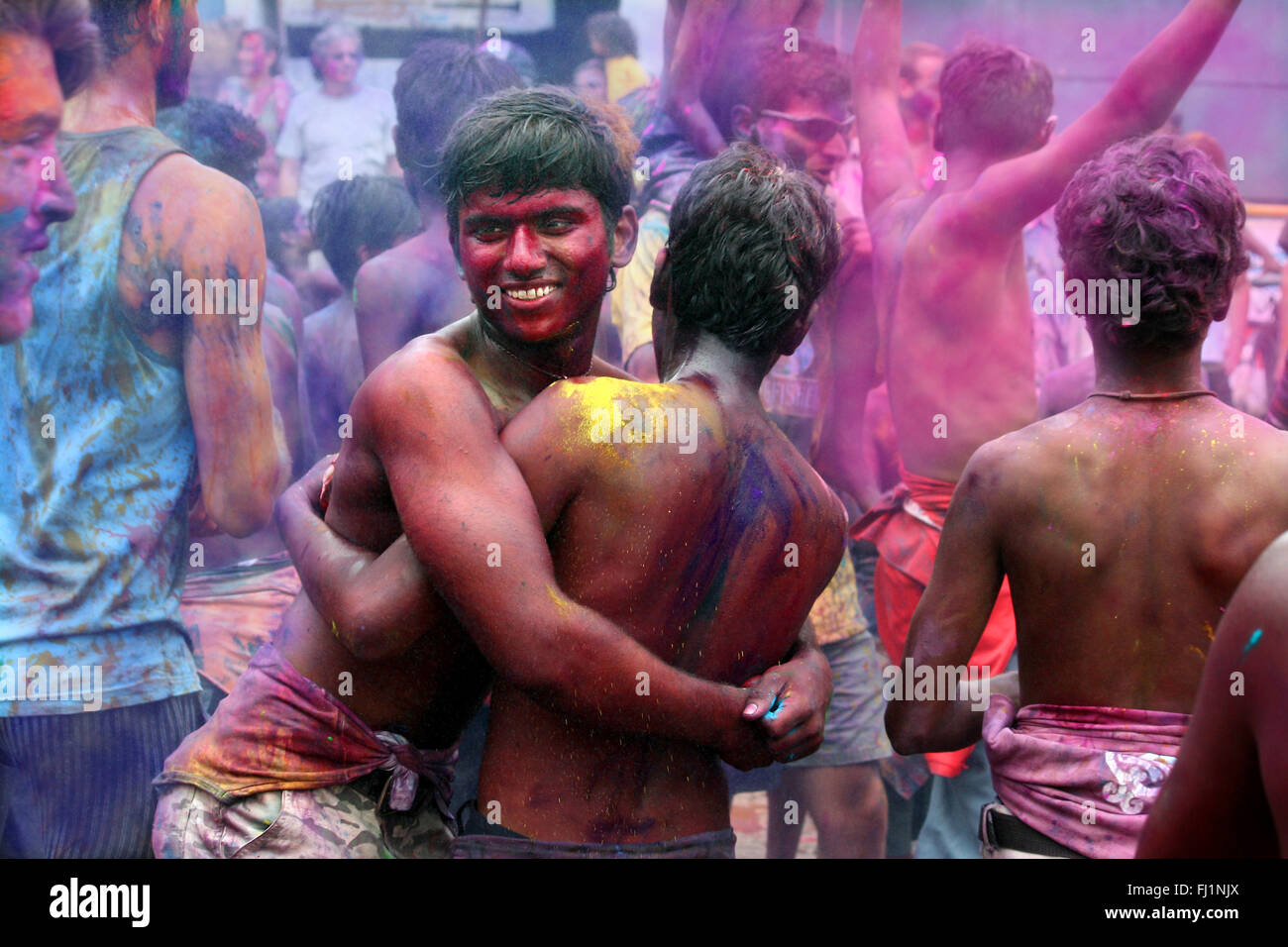 Deux hommes couverts de couleurs Holi s'embrassent lors de célébrations à Hampi , Inde Banque D'Images
