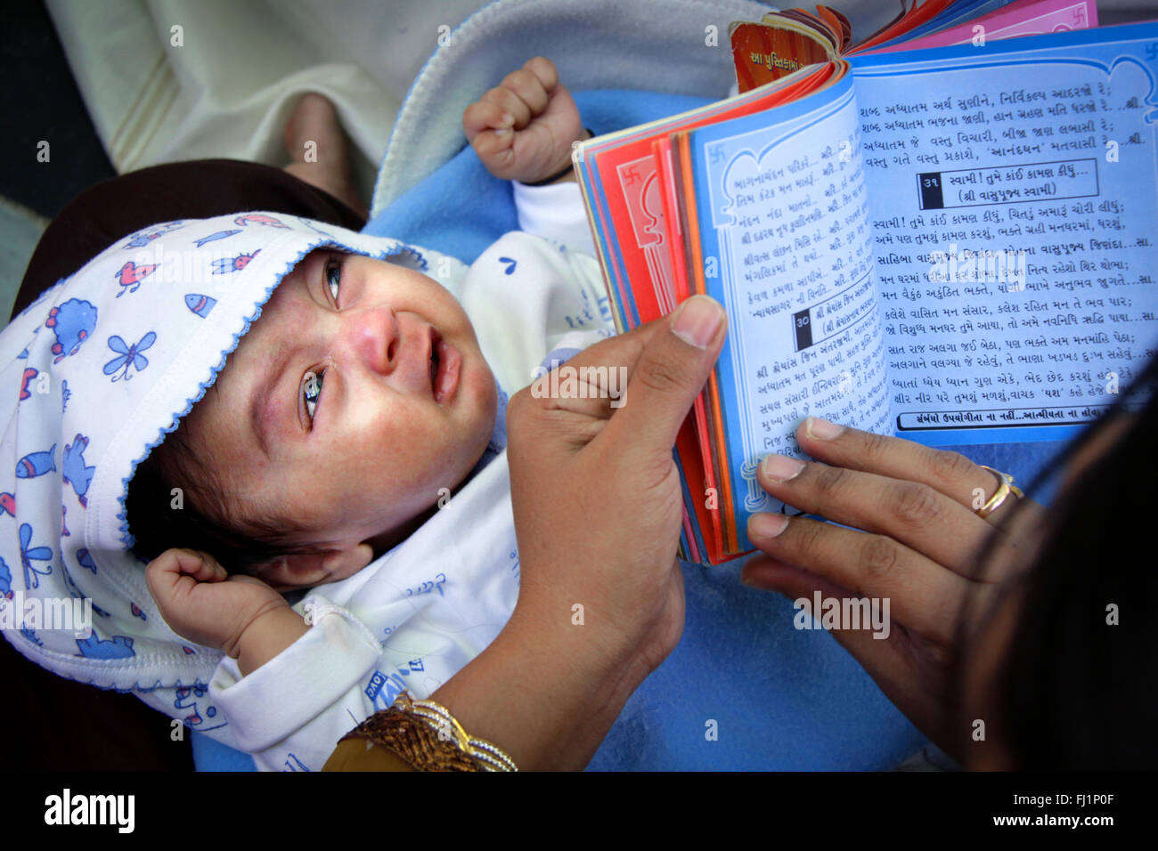 Un bébé pleure alors que mère lit la religion Jaïn en livre de temple Palitana , Inde Banque D'Images