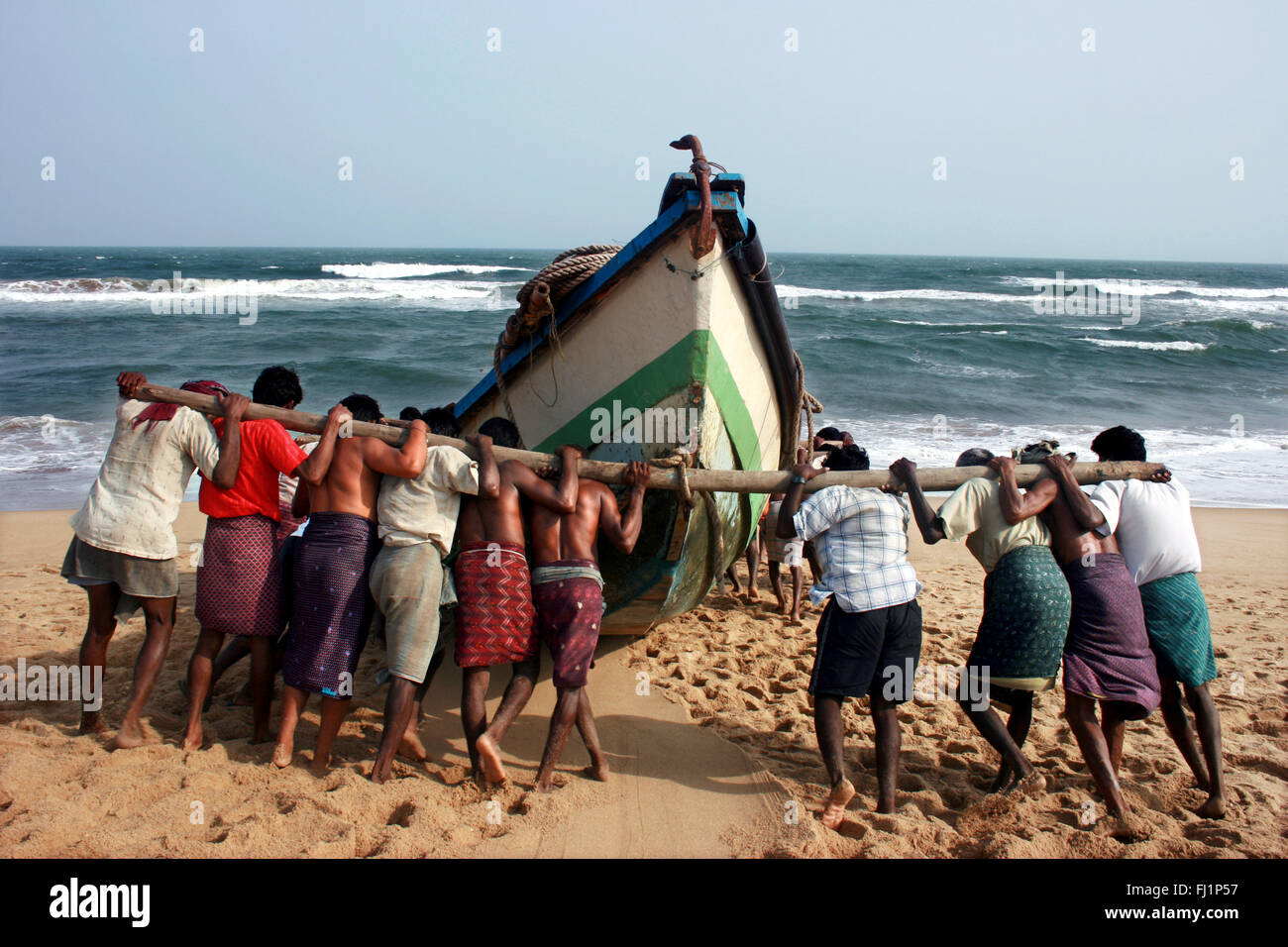 Pousser les pêcheurs à la mer bateau canoë avant de la pêche sur la plage de Puri, Orissa, Inde Banque D'Images