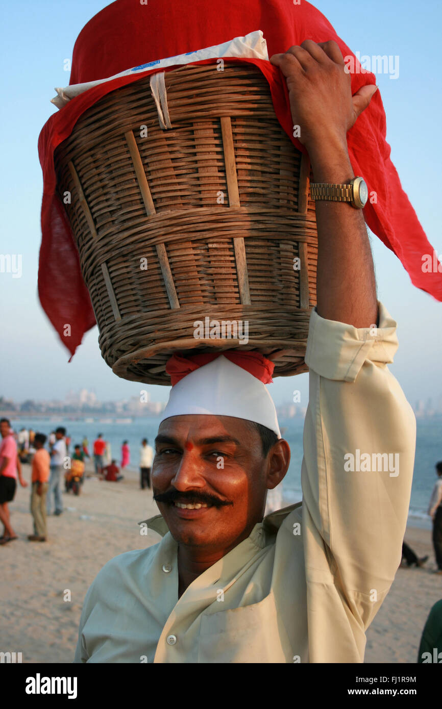 Smiling street food vendeur exerçant son immense panier sur Chowpatty beach , Mumbai , Inde Banque D'Images