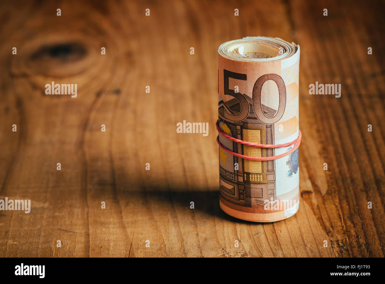Concept d'économiser de l'argent, j'ai roulé l'argent comptant avec bande élastique sur un bureau en bois, cinquante billets accueil personnels pile budget Banque D'Images
