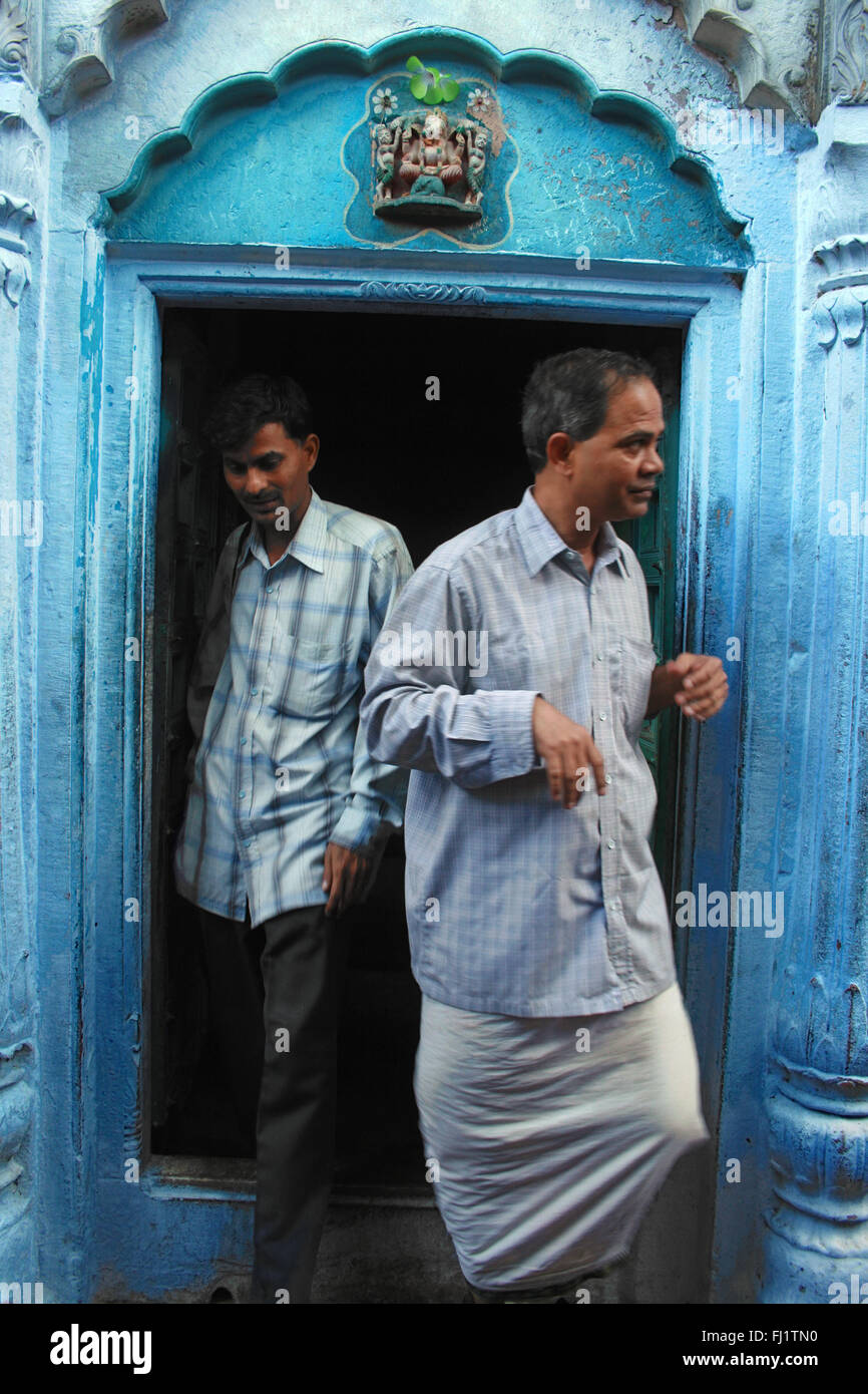 Les hommes de sortir d'une maison à l'architecture traditionnelle et porte , Varanasi, Inde Banque D'Images