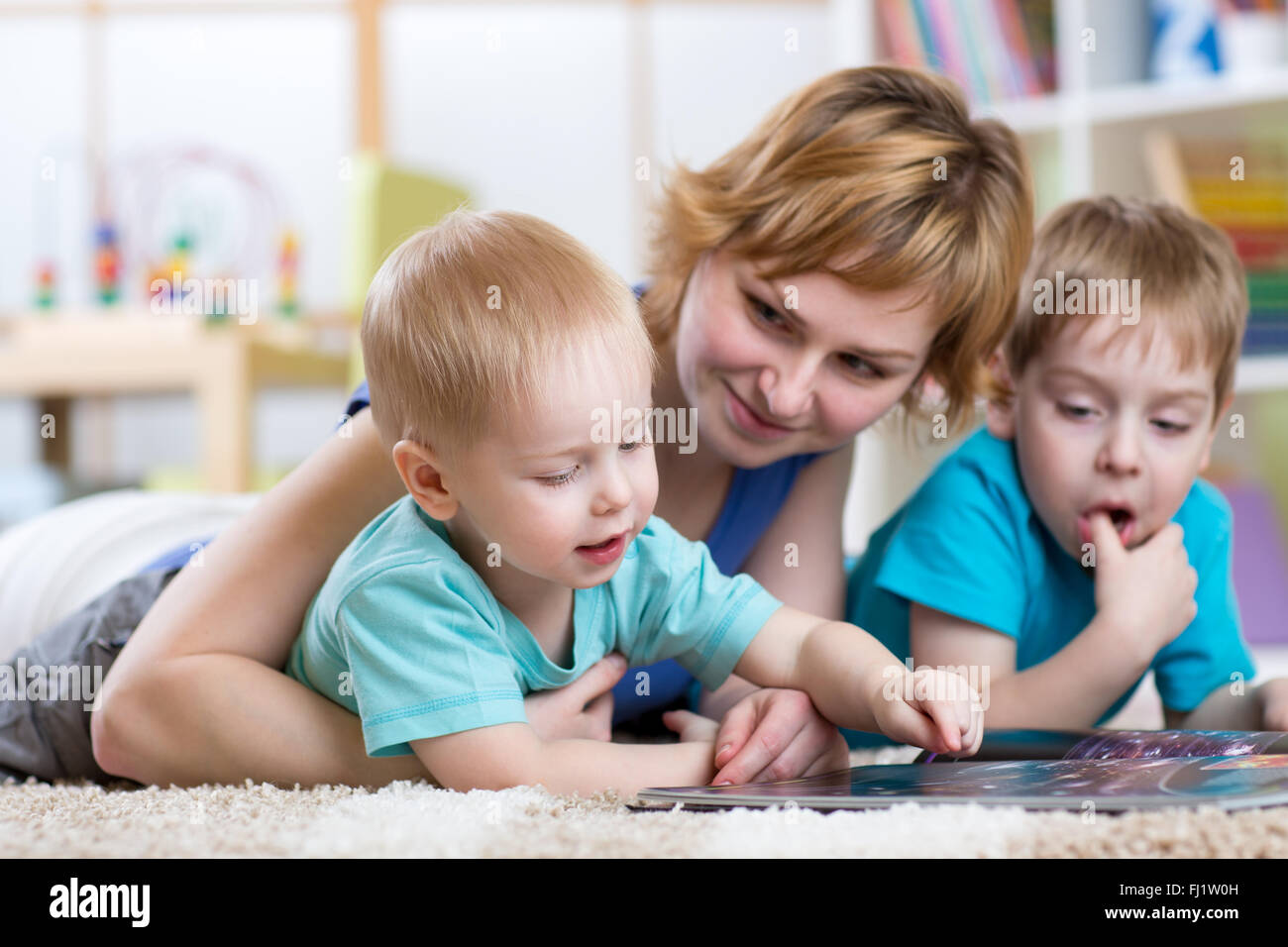 Jolie mère et ses deux fils les enfants lire ensemble Banque D'Images