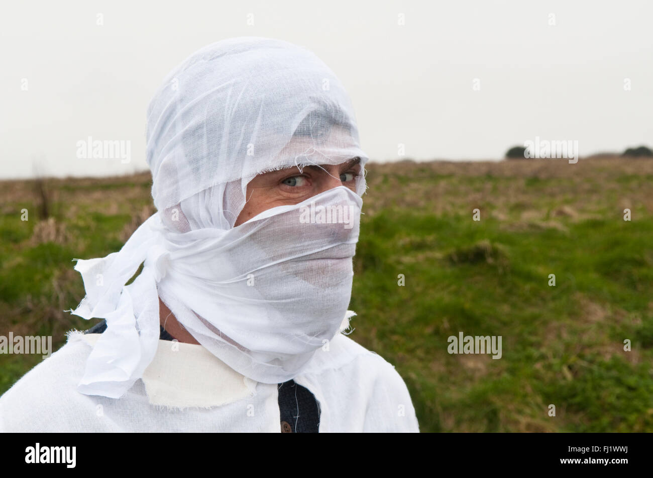 L'homme avec la tête dans les bandages blancs debout dans un champ Banque D'Images