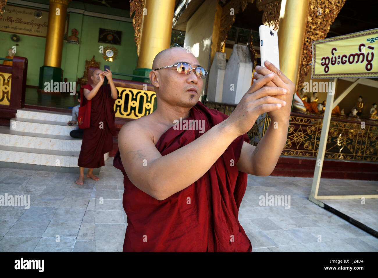 Le moine bouddhiste en tenant avec selfies je téléphone dans la pagode Shwedagon, Rangoon, Myanmar Banque D'Images