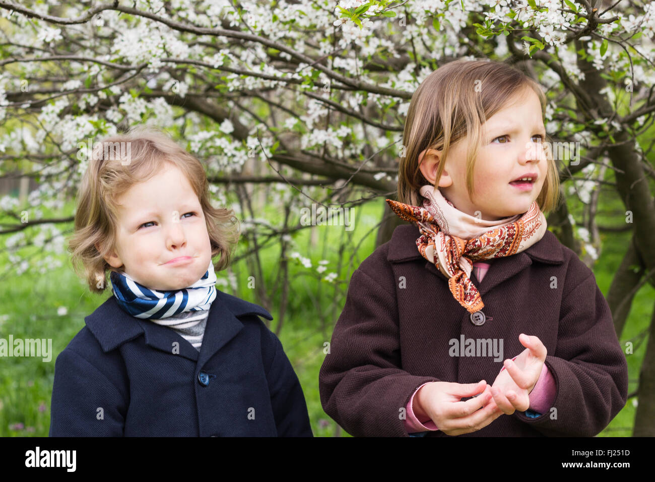 Cute little girls (sœurs 3 et 4 ans) près de la floraison des arbres. Banque D'Images