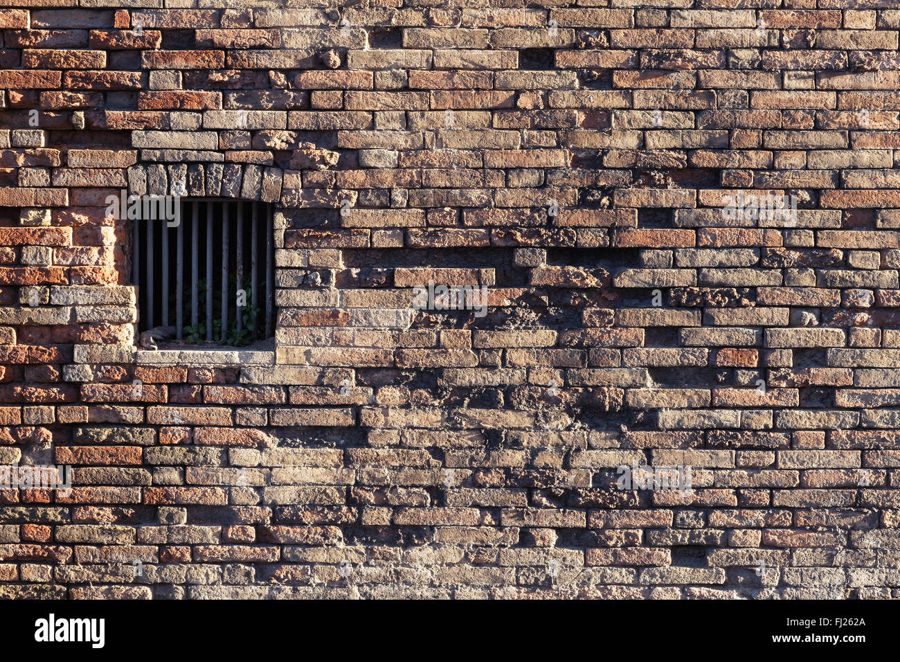 Mur de brique ancienne et fenêtre fermée avec des barres de métal Banque D'Images