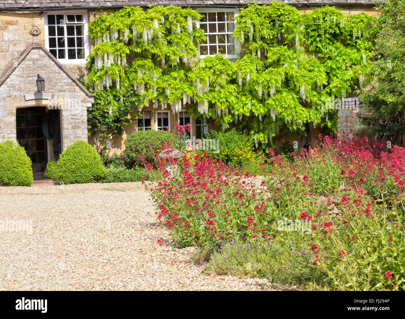 Cottage traditionnel anglais cour avec allée en gravier, de la pierre, de champignons jardin coloré de fleurs. Banque D'Images