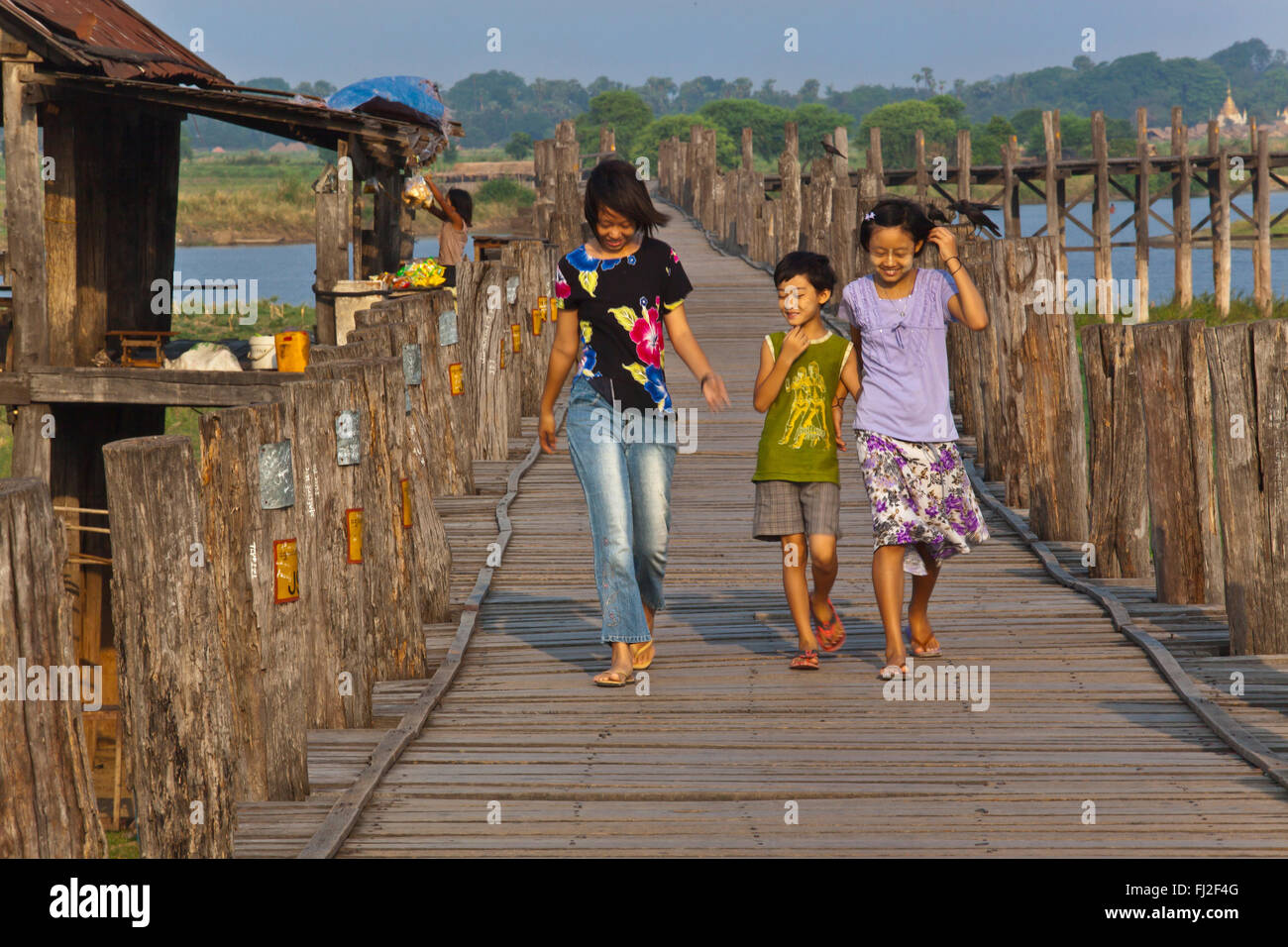 Les Birmans utilisent le pont en teck U BEINS de commuer en face du lac Taungthaman au lever du soleil - AMARAPURA, MYANMAR Banque D'Images