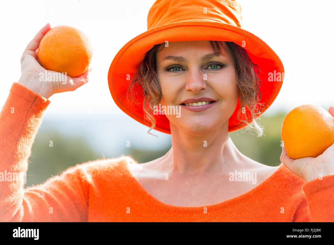 Femme au chapeau orange tenant deux oranges Photo Stock - Alamy
