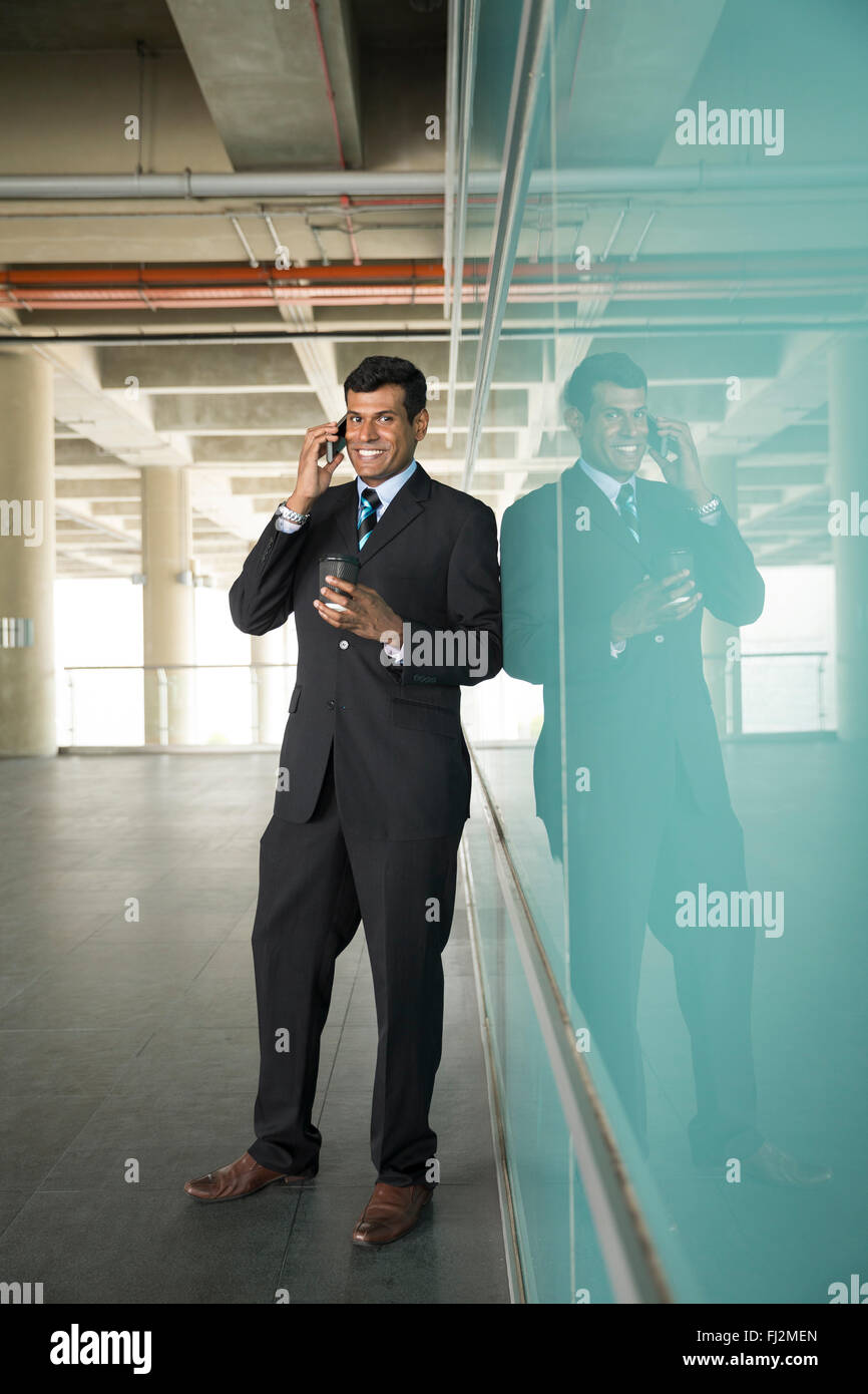 L'homme d'affaires indien à l'aide de son téléphone intelligent à l'extérieur dans la ville moderne. Banque D'Images