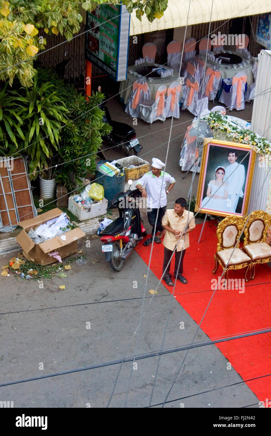 Un homme est en attente d'invités avec un cuisinier avant une cérémonie de mariage sur une rue de la ville de Kampong Cham, au Cambodge. Banque D'Images