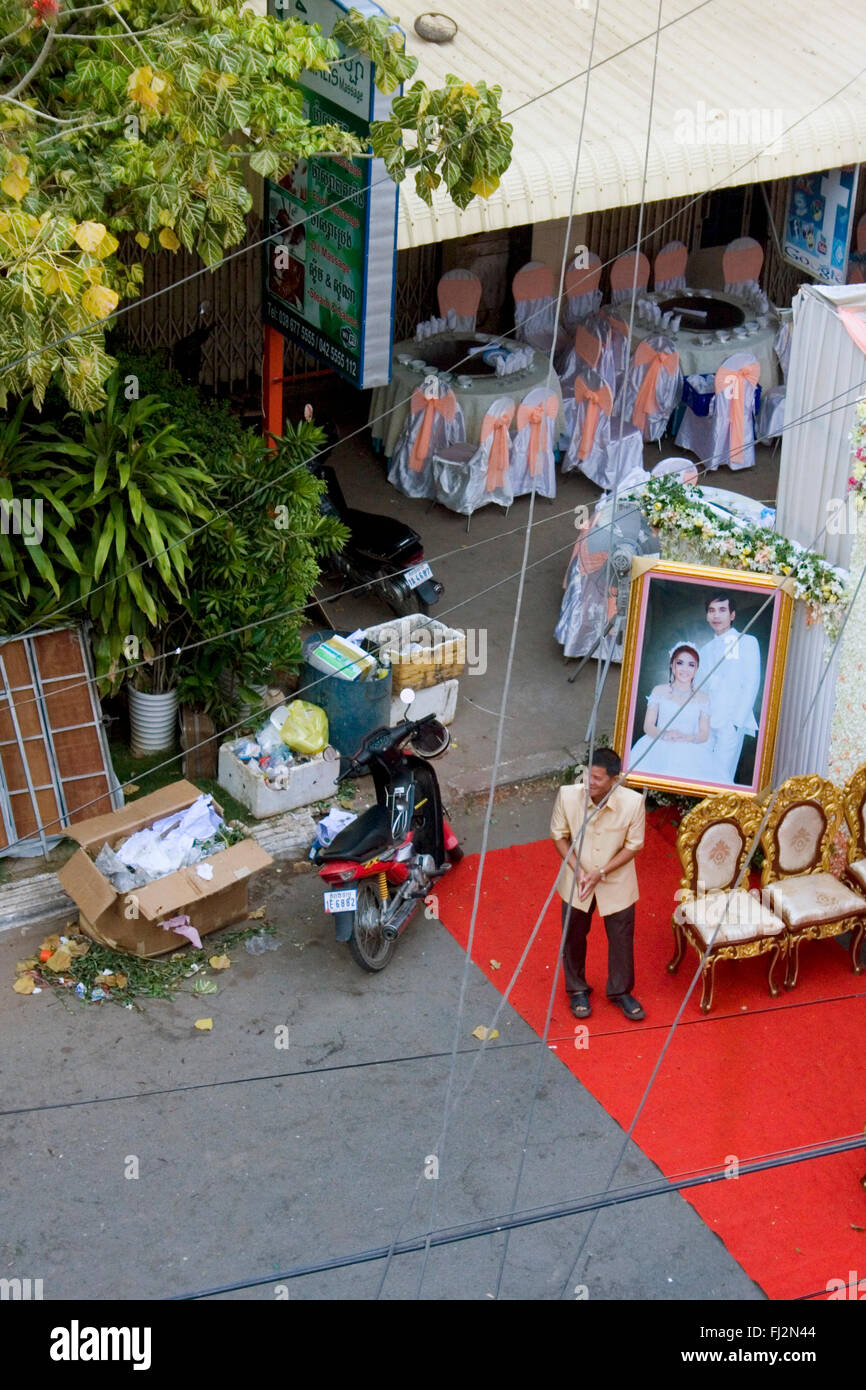 Un homme est en attente d'invités avant une cérémonie de mariage dans une rue bordée d'ordures dans Kampong Cham, au Cambodge. Banque D'Images