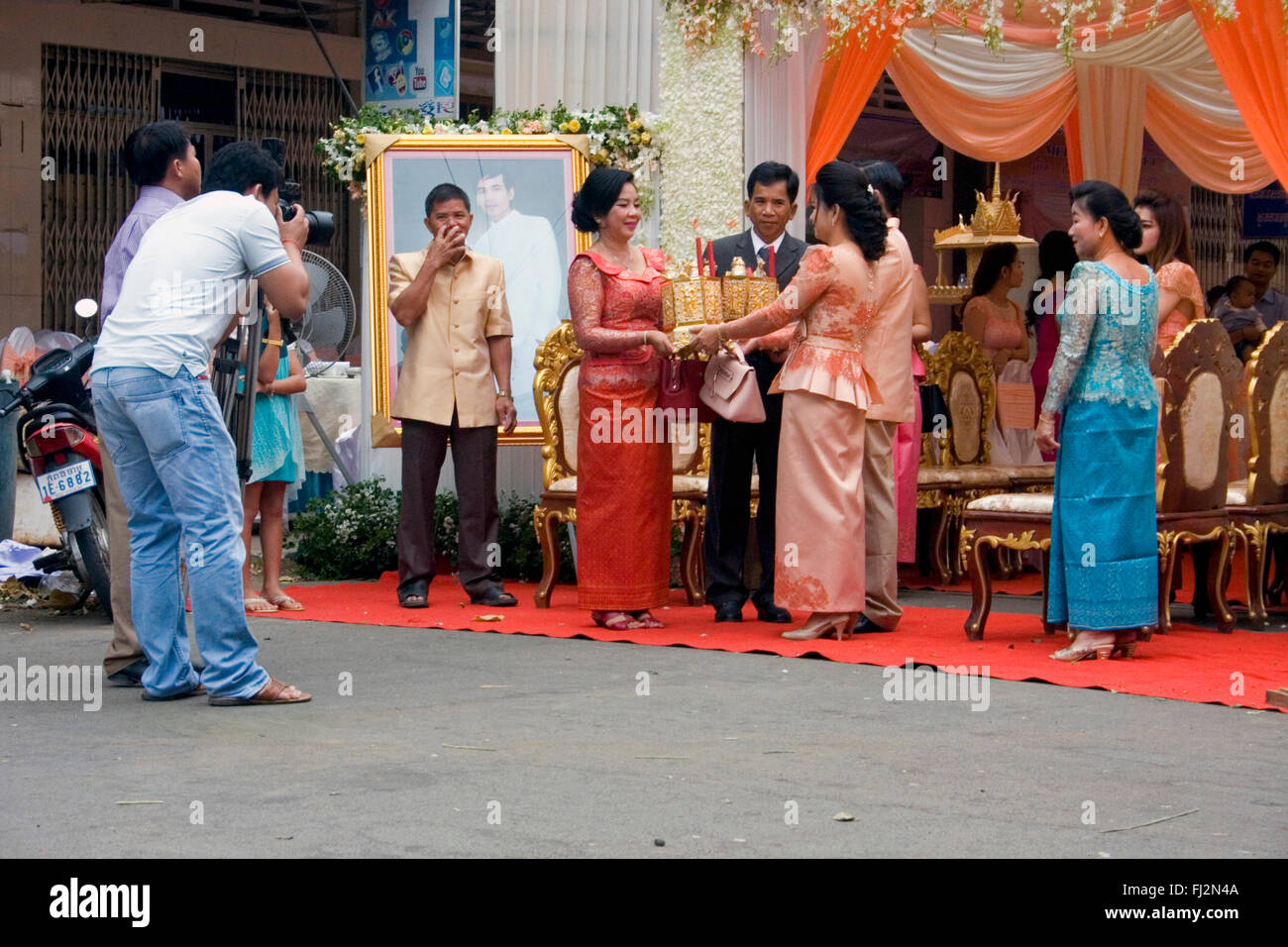 Une femme est un cadeau tout en assistant à une cérémonie de mariage traditionnel Khmer dans une rue à Kampong Cham, au Cambodge. Banque D'Images