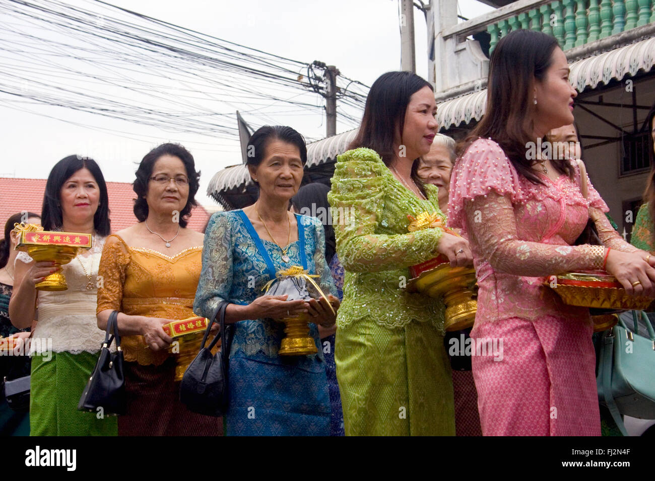 Les femmes dans une procession transportant des cadeaux assister à une cérémonie de mariage traditionnel Khmer dans une rue à Kampong Cham, au Cambodge. Banque D'Images