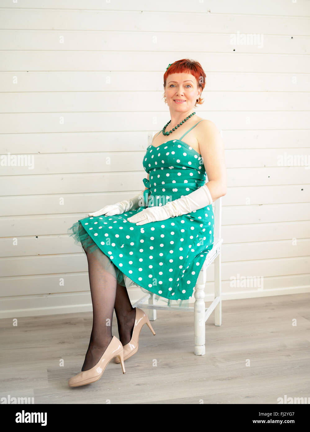 Jolie femme adulte assis sur une chaise, 50s style Banque D'Images