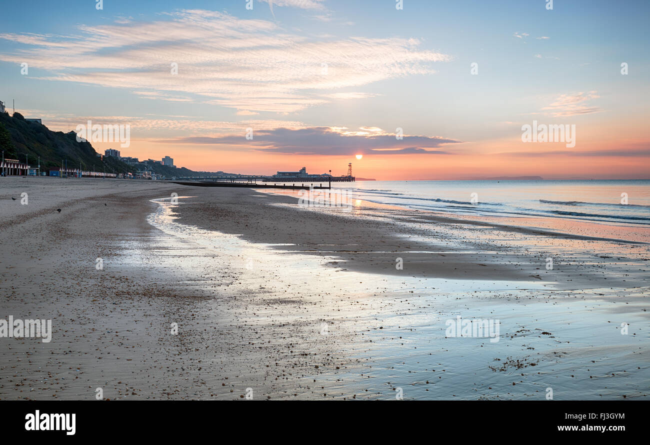 Le lever du soleil sur la plage de Bournemouth avec la jetée dans la distance Banque D'Images
