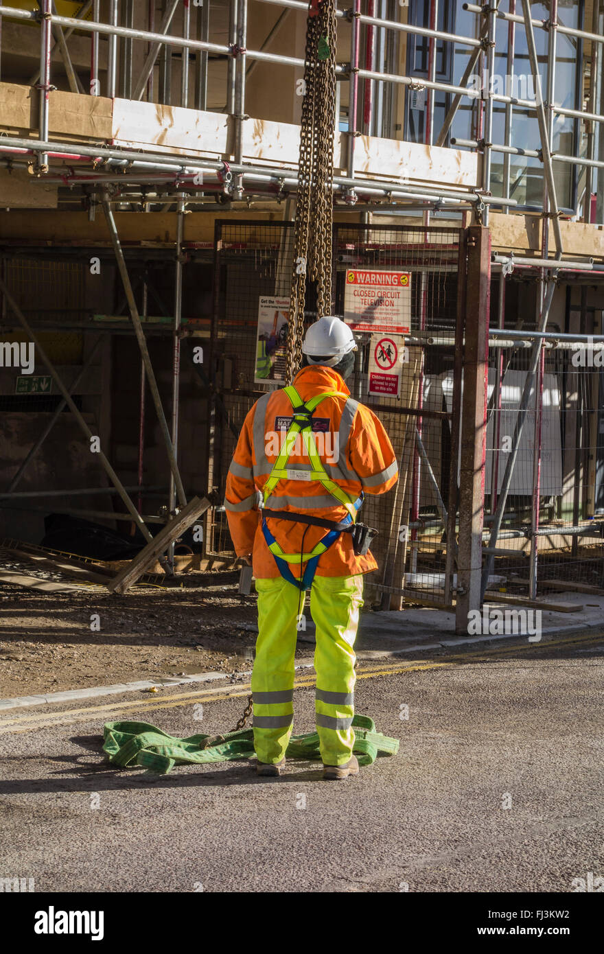 Travailleur de la Construction avec casque de sécurité l'article ci-dessous d'un palan à l'extérieur de l'échafaudage sur le nouveau bâtiment, Bournemouth, England, UK Banque D'Images