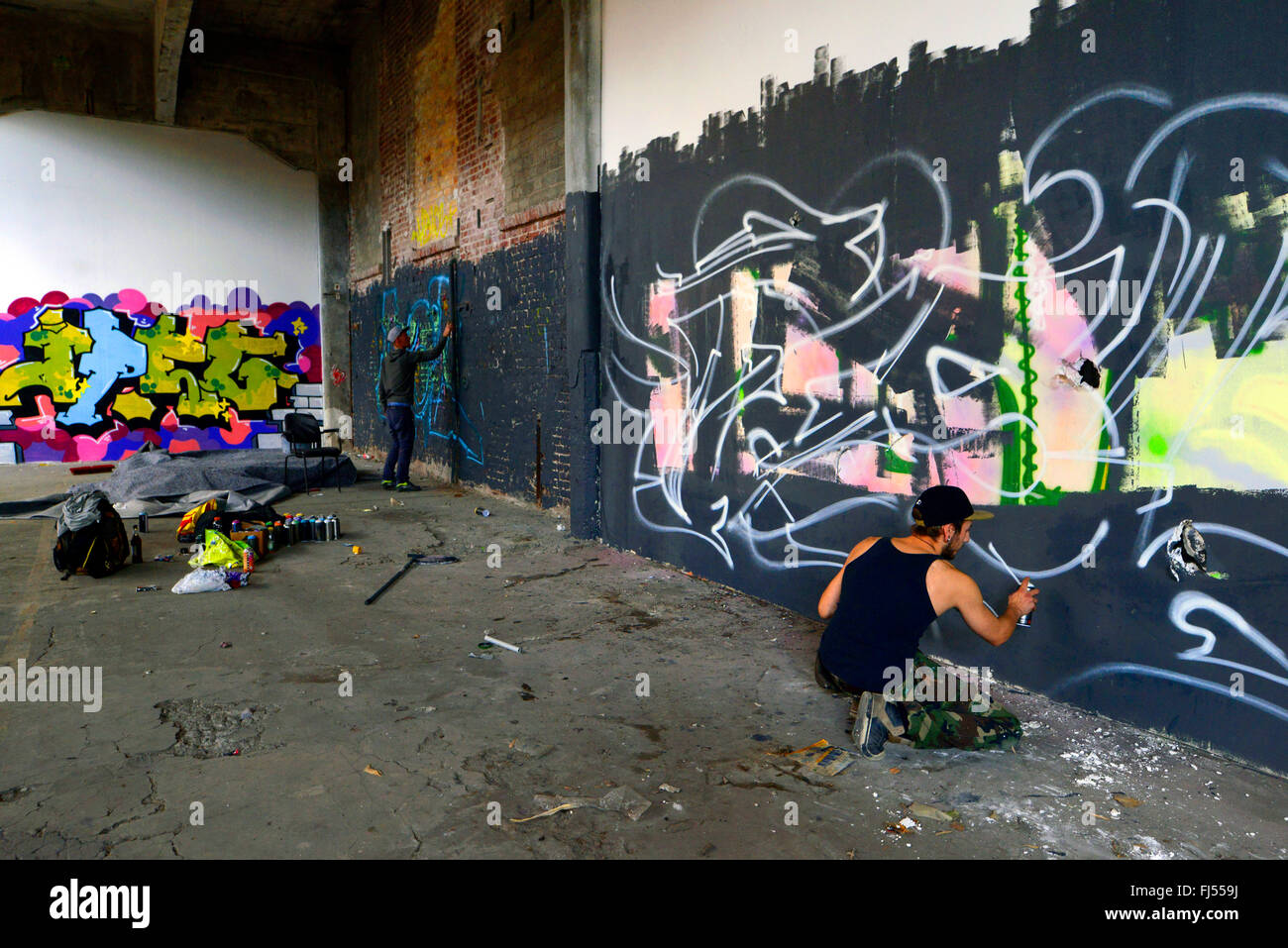 La pulvérisation des hommes à un mur de graffiti dans un abandonend terre industrielle, l'Allemagne, en Rhénanie du Nord-Westphalie, Duesseldorf Banque D'Images