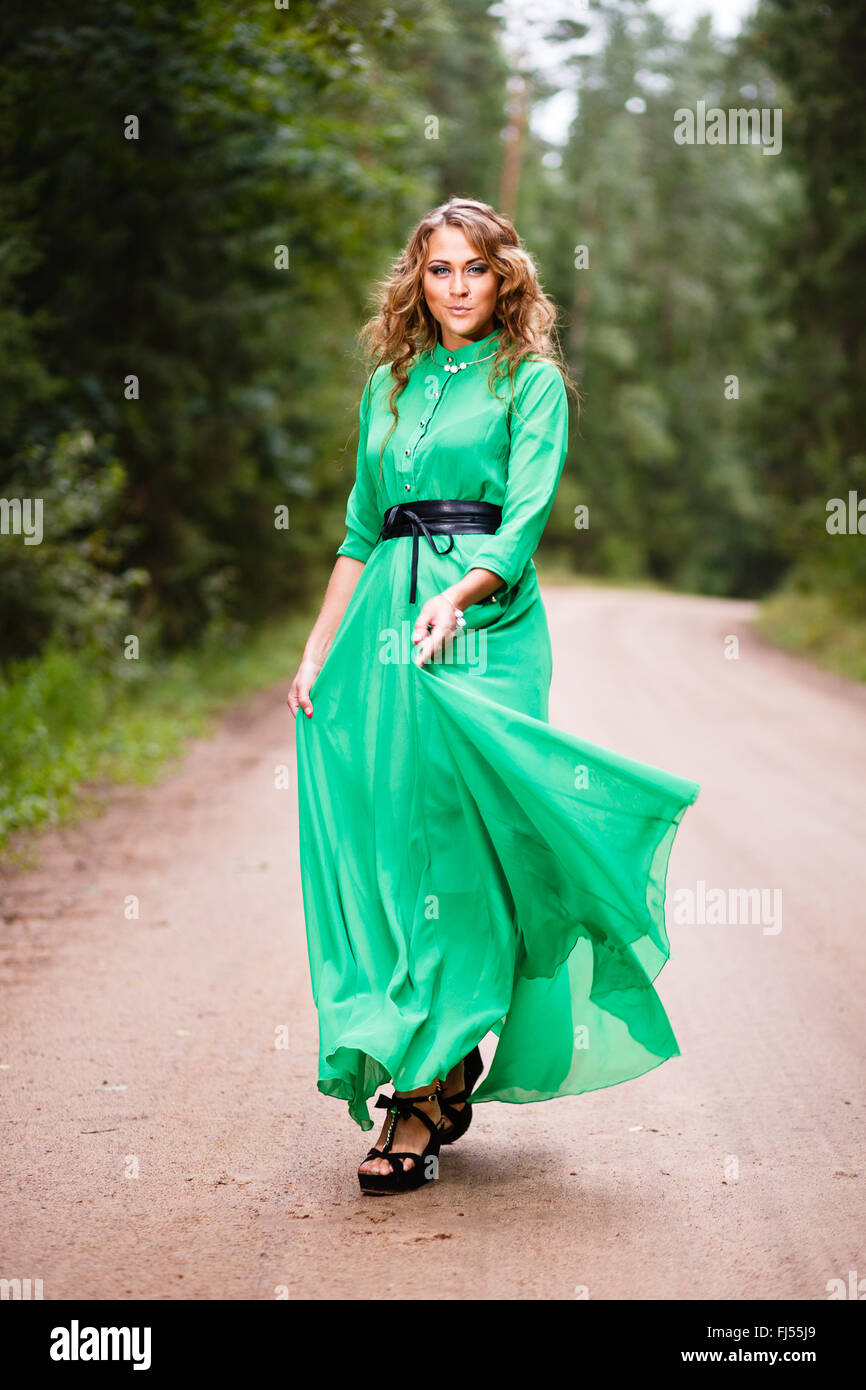 Femme en robe verte sur route forestière. Banque D'Images