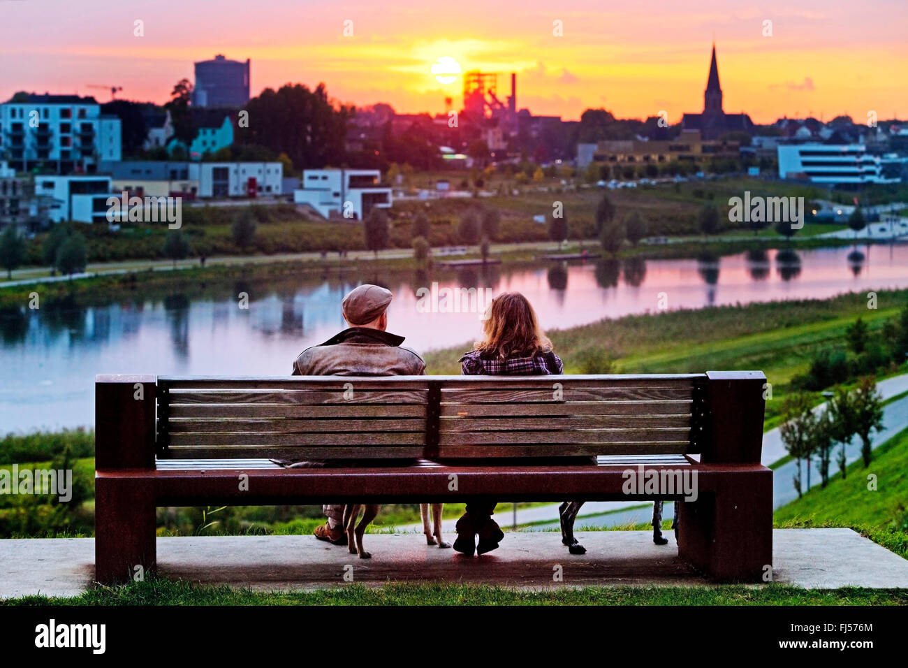 Deux personnes assises sur un banc de parc au lac Phoenix et profiter de la vue au coucher du soleil, de l'Allemagne, en Rhénanie du Nord-Westphalie, Ruhr, Dortmund Banque D'Images